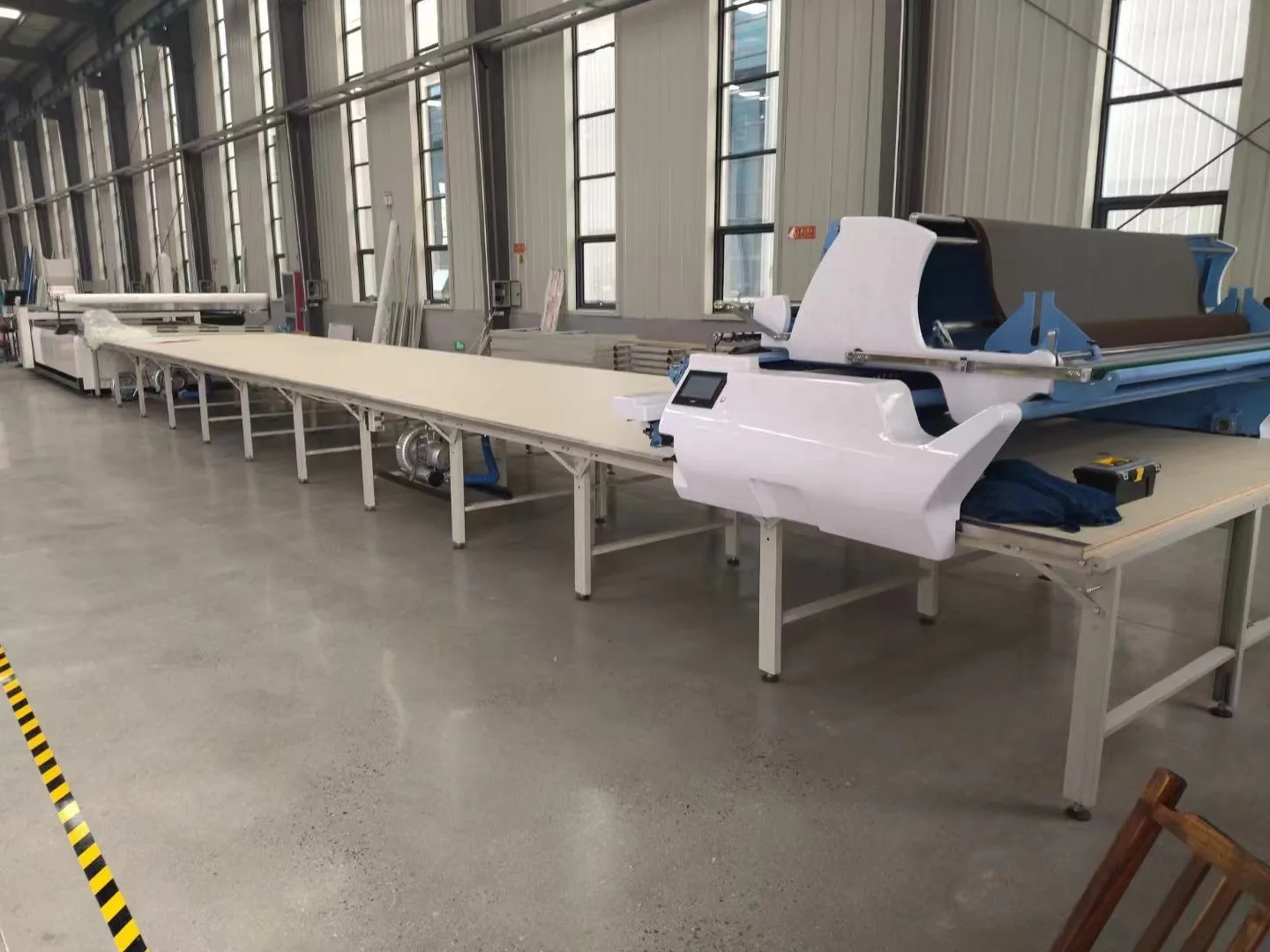 機頭を備えた長い作業台と敷き込まれた材料
